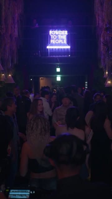 The Powder to the People neon sign above a full room